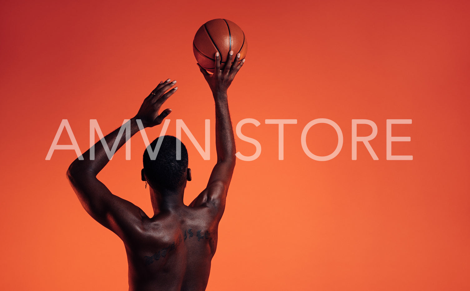 Rear view of a muscular athlete prepare to throw a basket ball in studio