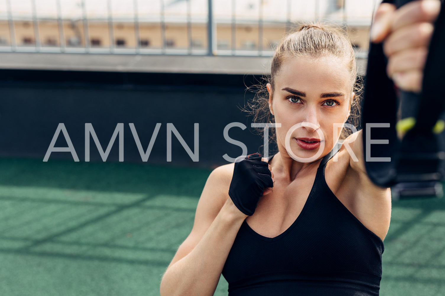 Young woman doing exercises on a rooftop. Fitness female working out outdoors using suspension strap for lifting.	
