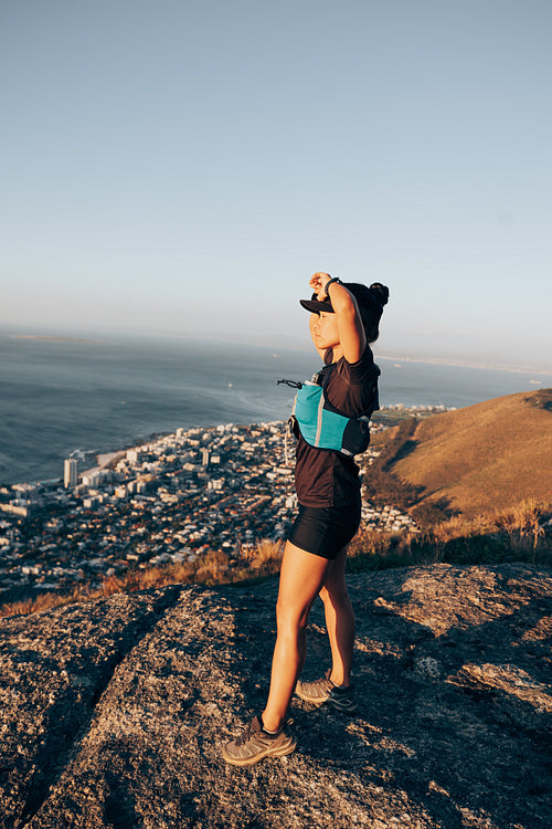 Woman relaxing on hill after hiking enjoying the view at sunset