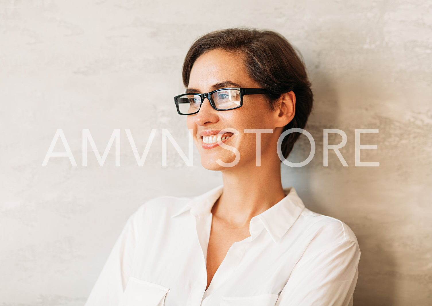 Cheerful businesswoman wearing eyeglasses. Portrait of a smiling entrepreneur leaning against a wall wearing formal wear.