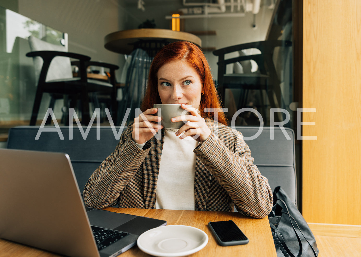 Businesswoman in a jacket holding a cup sitting at cafe in the morning