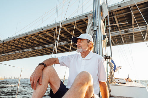 Mature man looking away while sitting on his sailboat