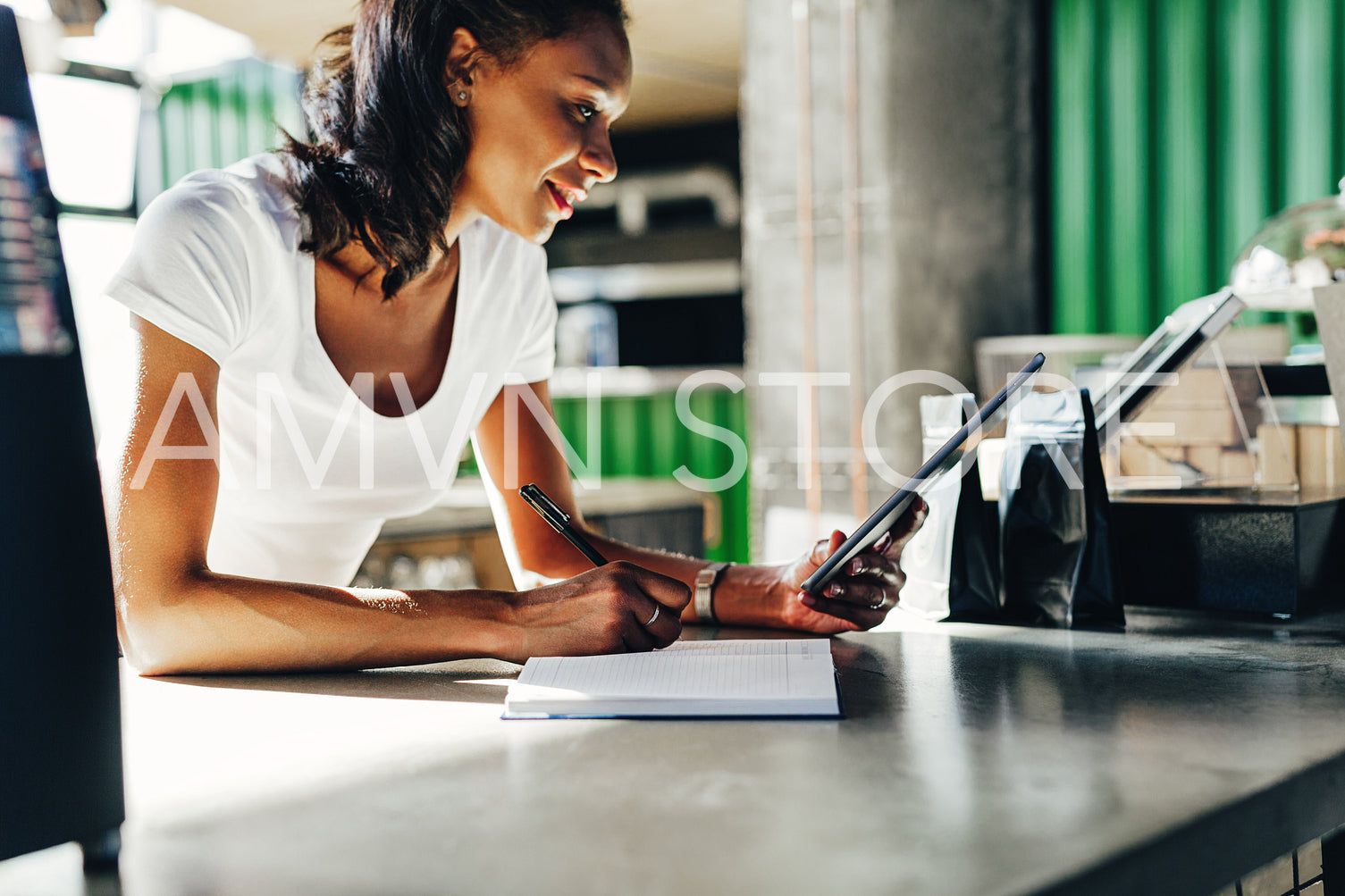 Woman reviewing business files on digital tablet at the counter in coffee shop	