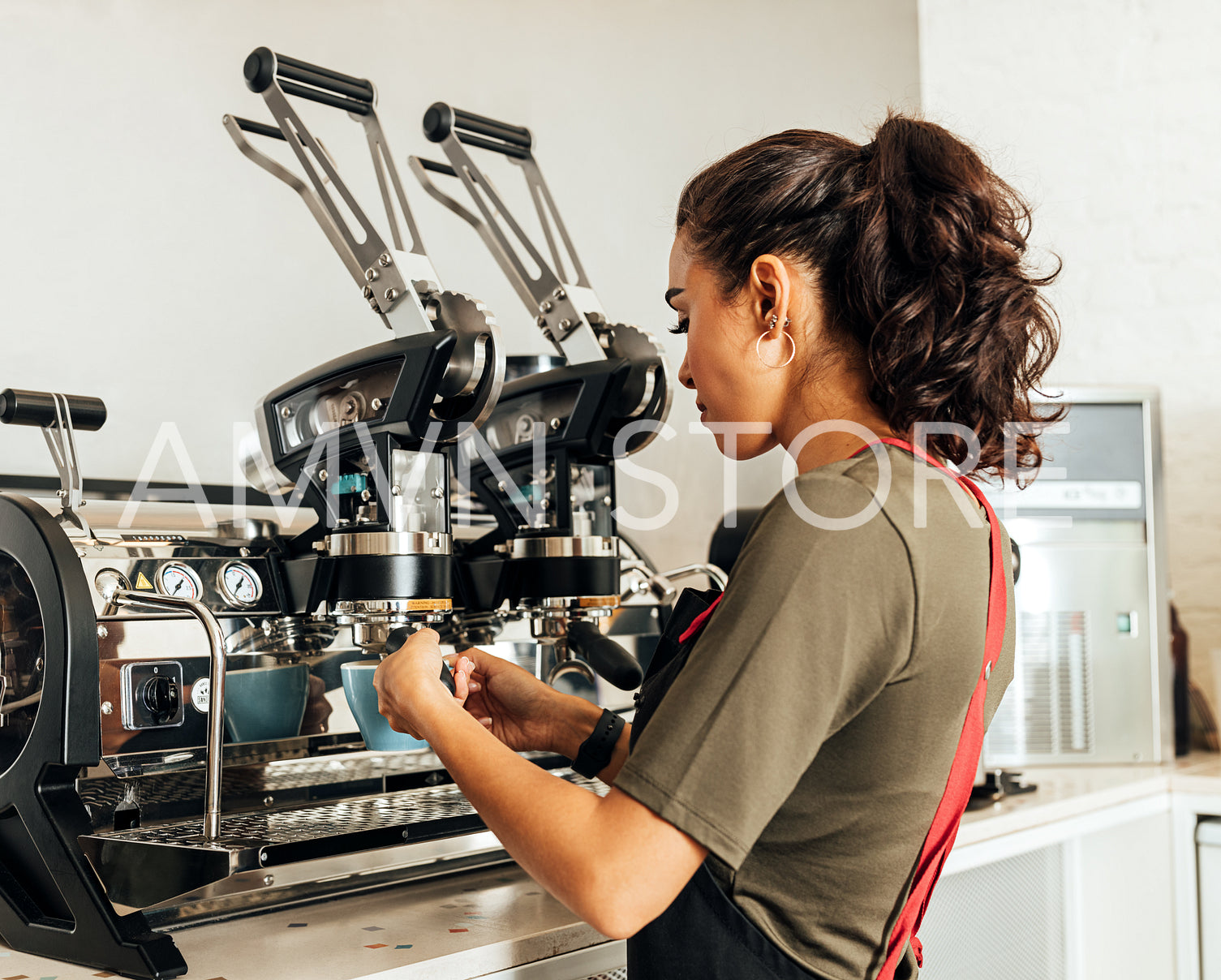 Female barista using a coffee machine to make an espresso. Young cafe worker preparing a beverage.	