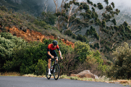 Young male cyclist practicing in wild terrain. Professional triathlete riding road bike.