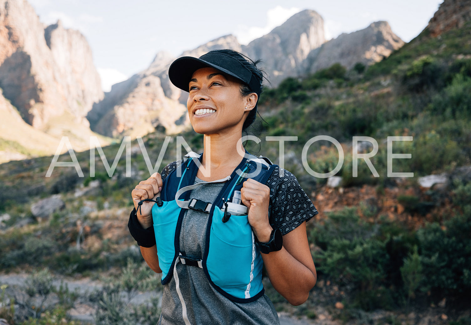 Smiling middle-aged female relaxing during a hike, enjoying the view. Female in hiking sportswear looking on mountains.