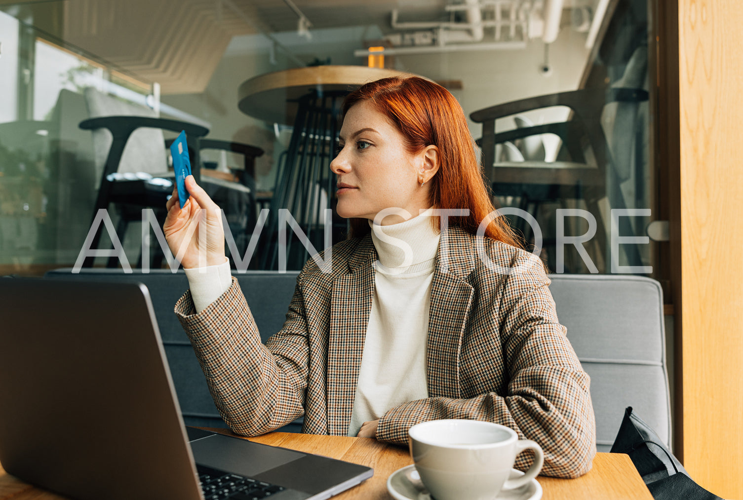 Businesswoman sitting at a table and holding a credit card, willing to pay for her breakfast