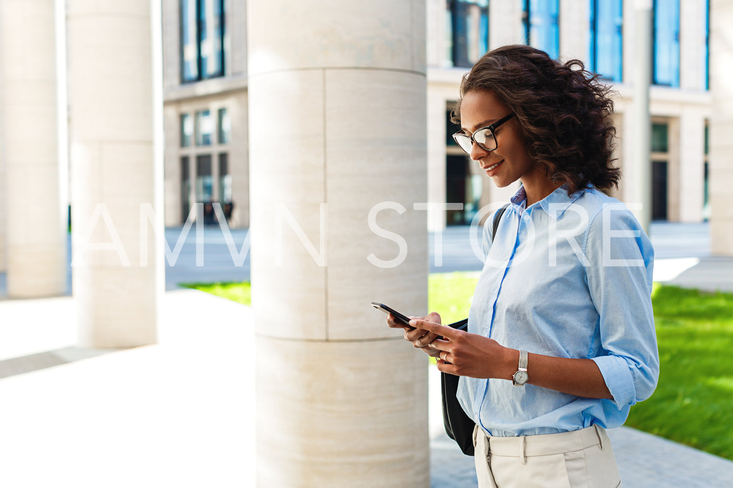 Portrait of modern businesswoman standing outdoors and texting on cell phone	