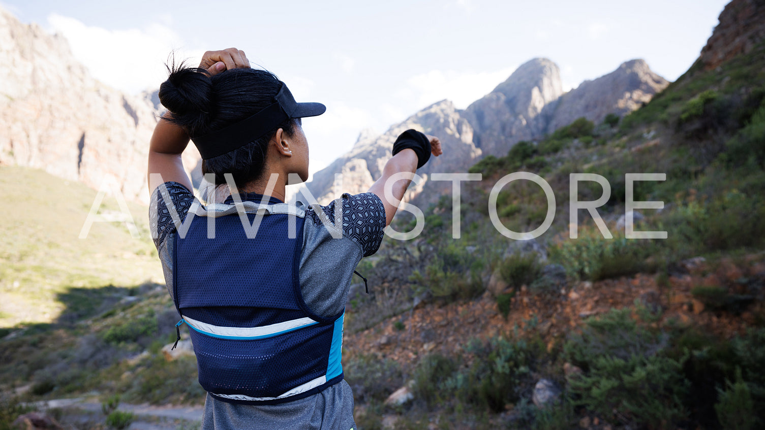 Rear view of sportswoman looking for a path and pointing to the mountain