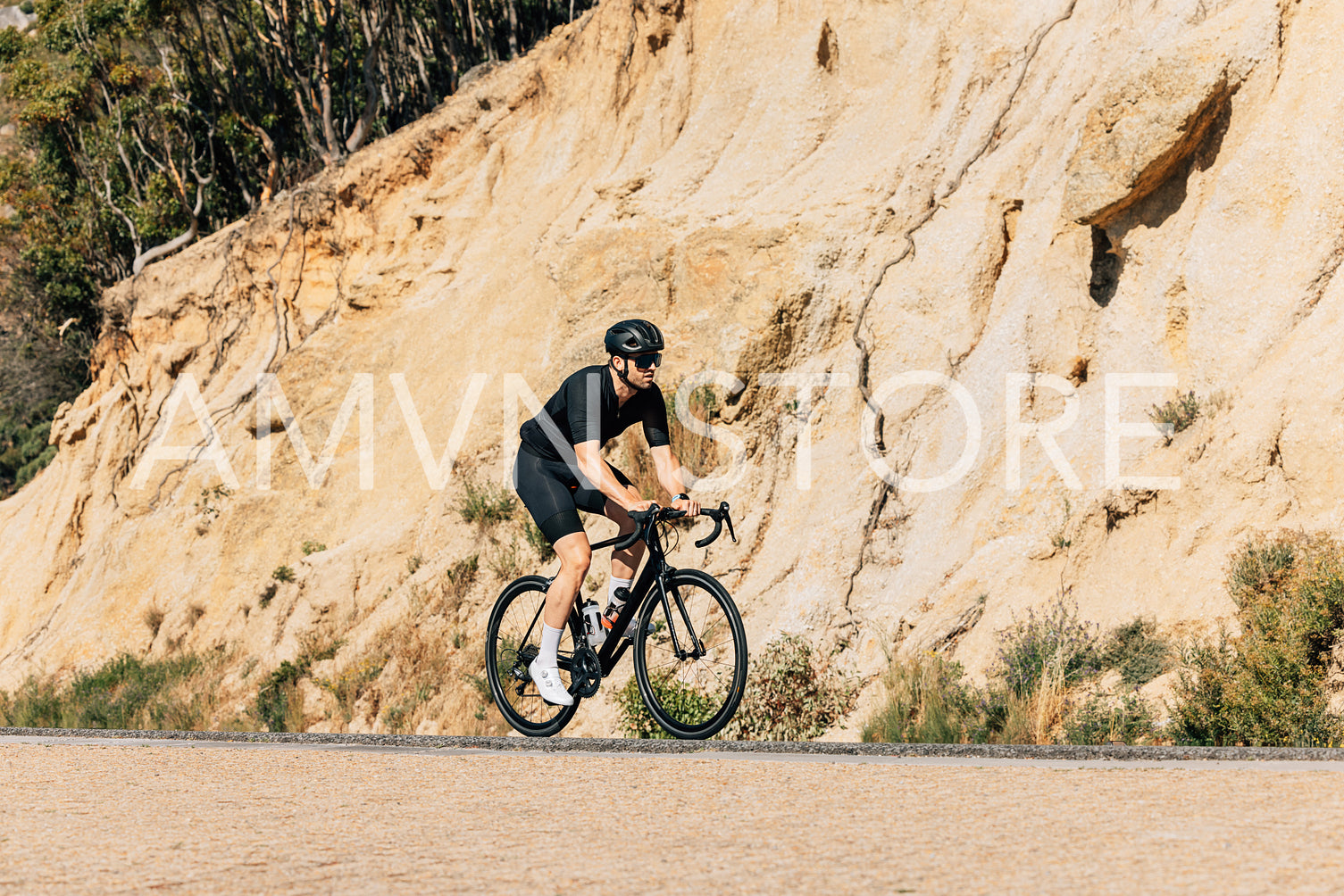 Triathlete riding his road bike on an empty road. Sportsman exercising on bicycle outdoors.