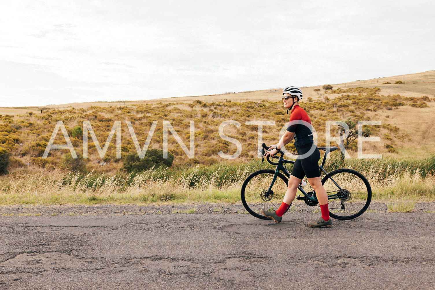 Side view of a professional female cyclist walking with bike on a country road