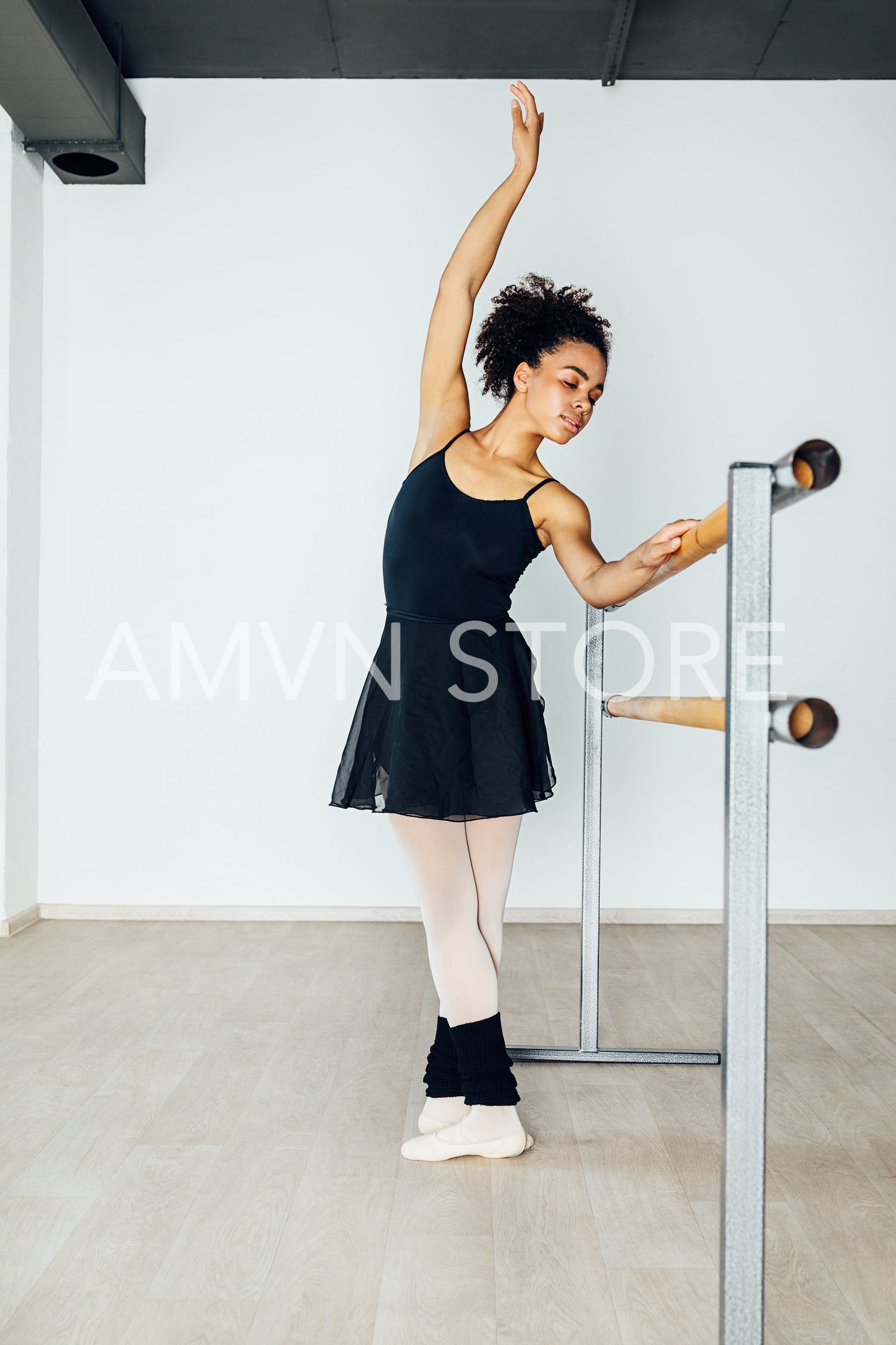 Young artist practicing ballet moves in the studio at barre	