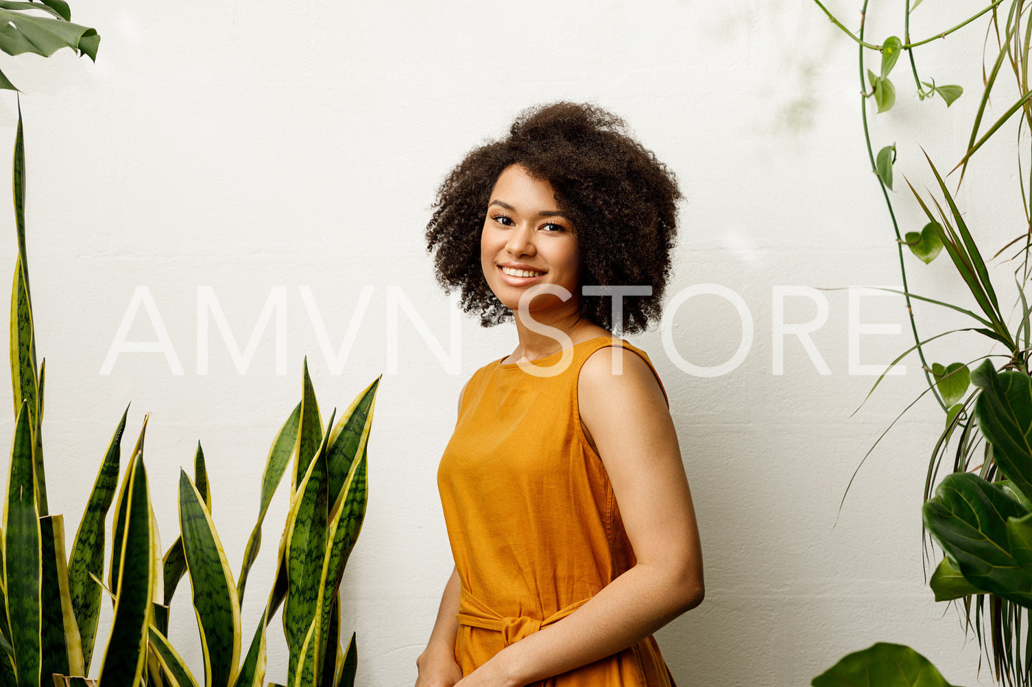 Beautiful smiling woman posing at the wall with plants