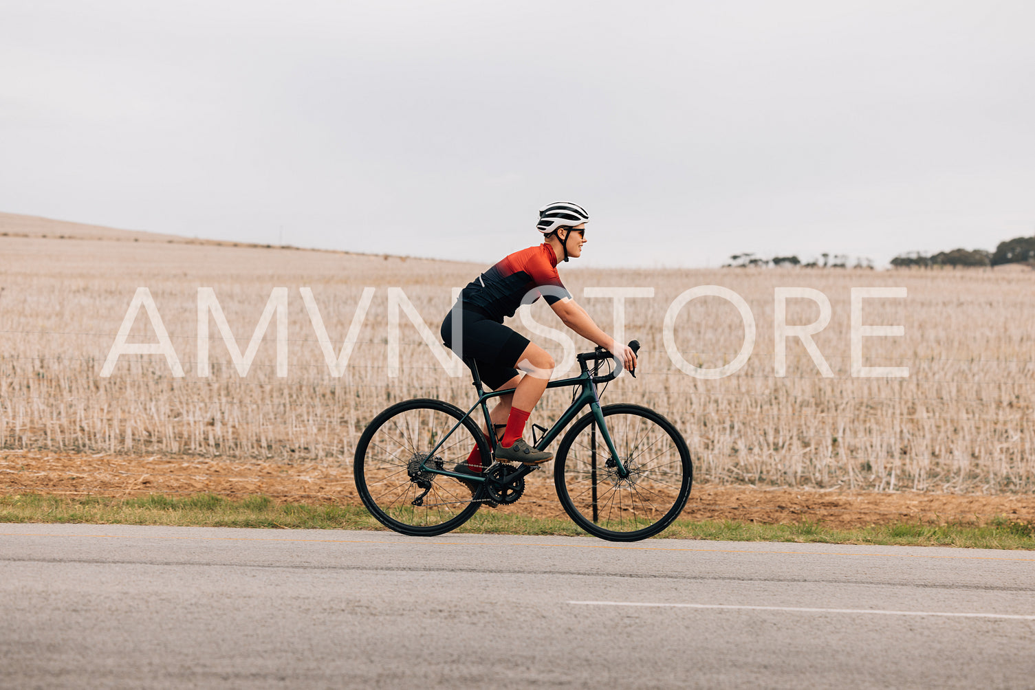 Side view of a female cyclist riding bike against field