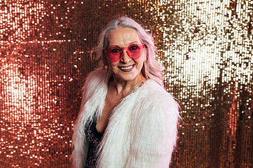 Stylish senior woman in white fur coat wearing pink eyeglasses h