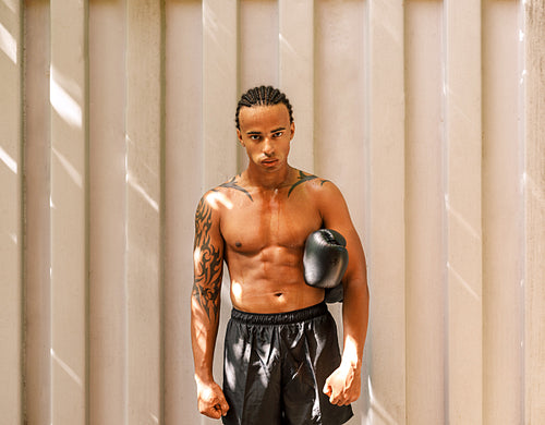 Young kickboxer standing at a wall after training looking at the camera