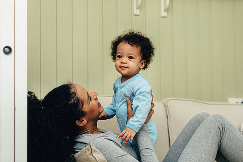 Young mother holding her cute son while he stands on her hips