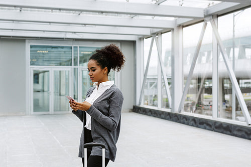 Young businesswoman waiting in airport terminal, checking mobile phone