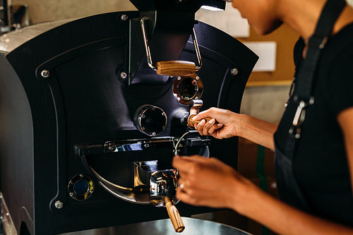 Unrecognizable woman controlling a roasting coffee process, operating a machine