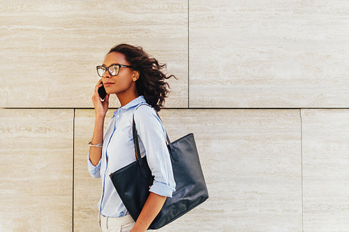 Side view of confident businesswoman walking on city street, carrying bag on shoulder