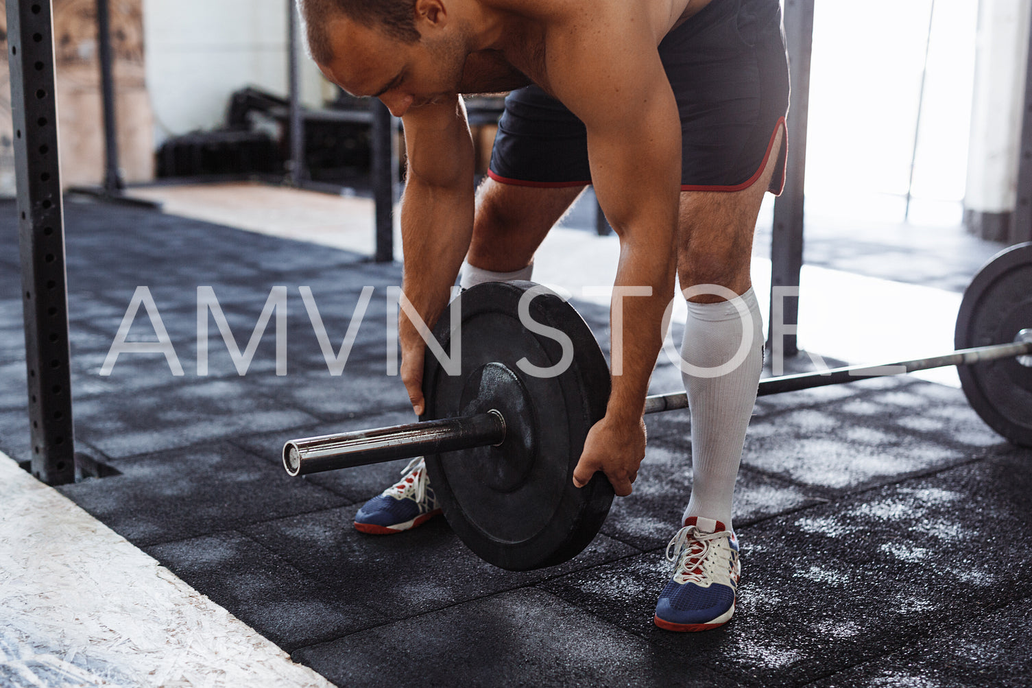 Cropped shot of man preparing barbell in training gym	