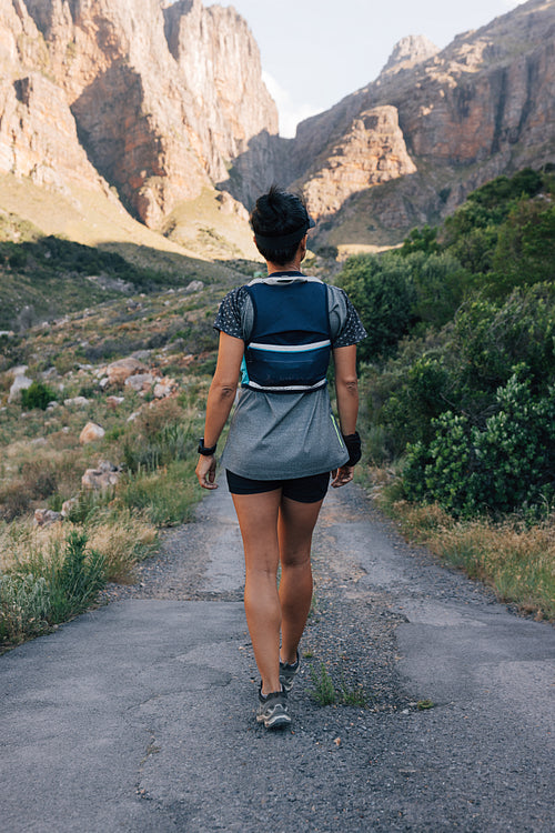 Woman hiker walking on abandoned road in valley