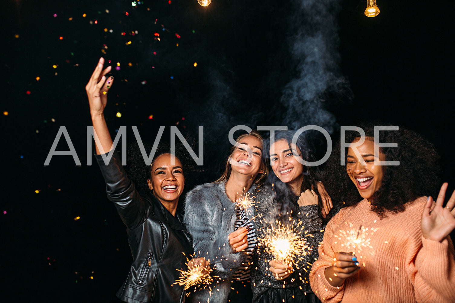 Four diverse women having fun outdoors holding sparklers and throwing confetti