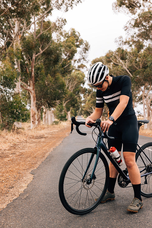 Sportive female cyclist examining on board computer system on bi