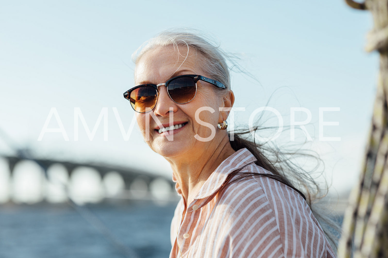 Beautiful mature woman in sunglasses looking at camera and smiling outdoors	