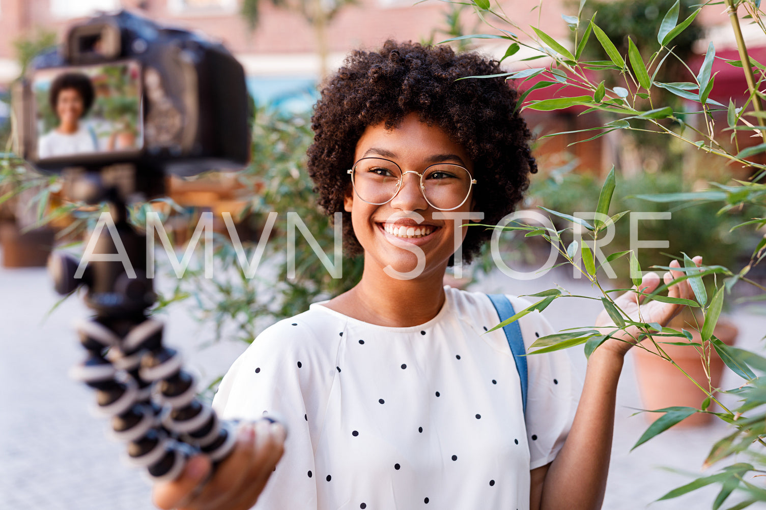 Blogger recording video from vacation. Smiling woman holding a digital camera on tripod.	