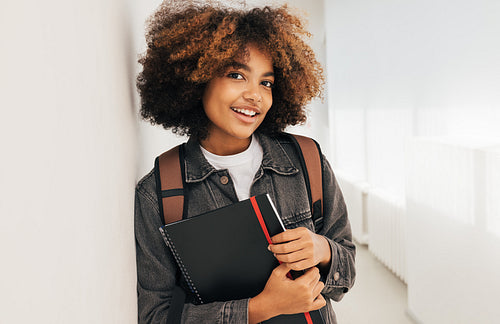 Portrait of a smiling girl standing at wall in school. Confident female standing in high school.