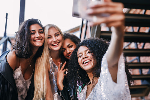 Happy friends looking at smartphone. Smiling women taking a selfie.