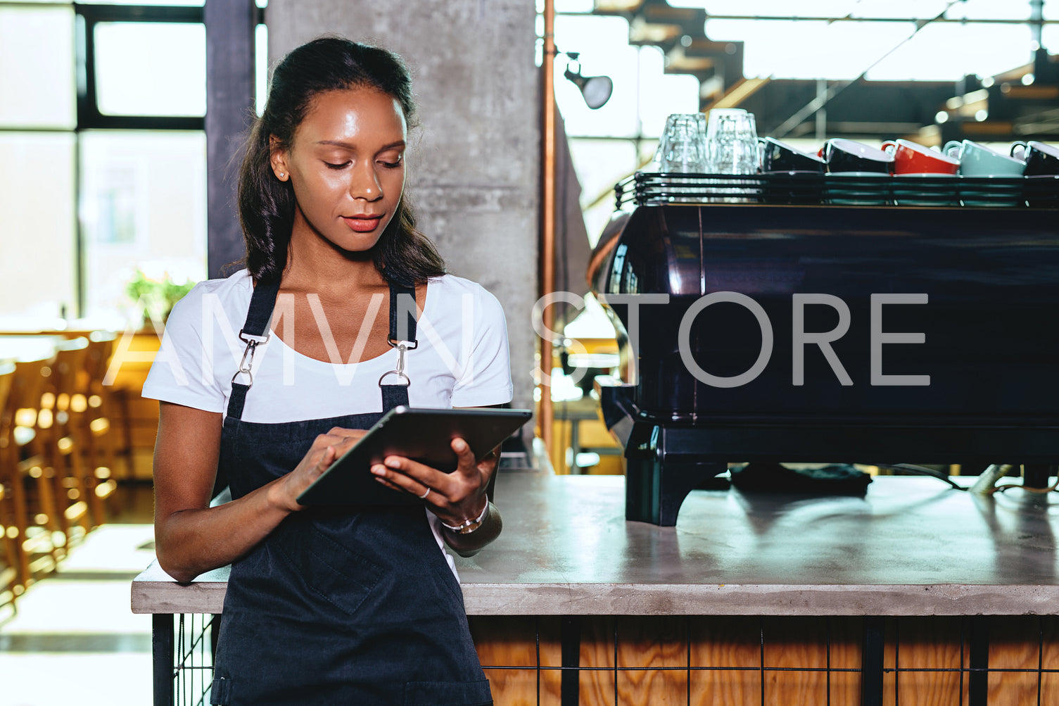 Young barista using digital tablet. Waitress standing by the coffee machine.	