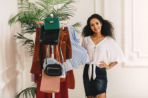 Smiling stylist standing at her wardrobe and looking at camera