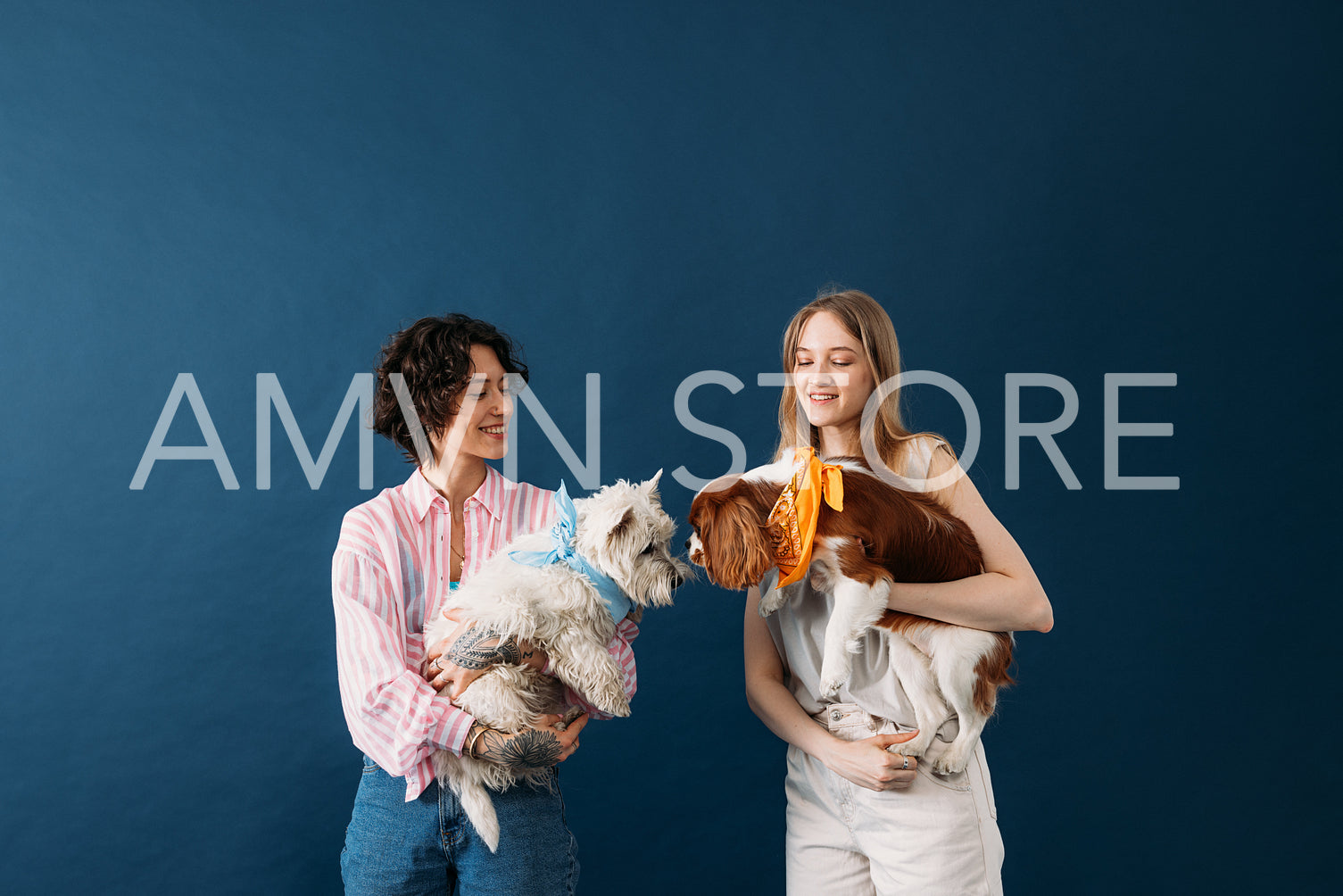 Two women holding their dogs in studio. Females with cute little