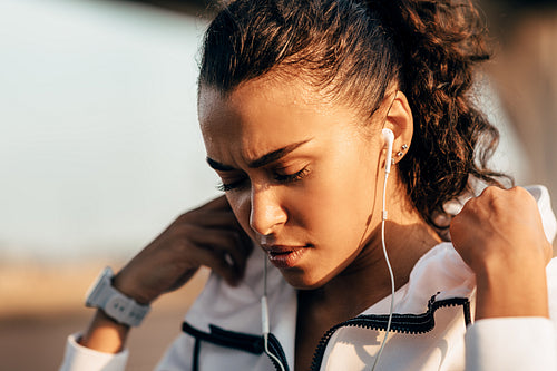 Tired sportswoman wearing a hoodie jacket. Young female athlete taking a break during workout with closed eyes.