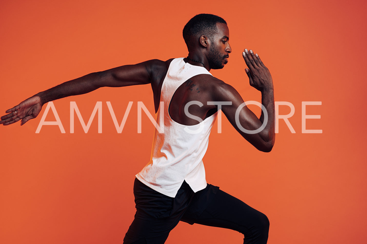 Close up of male runner exercising over an orange background. Young athlete sprinting in the studio.