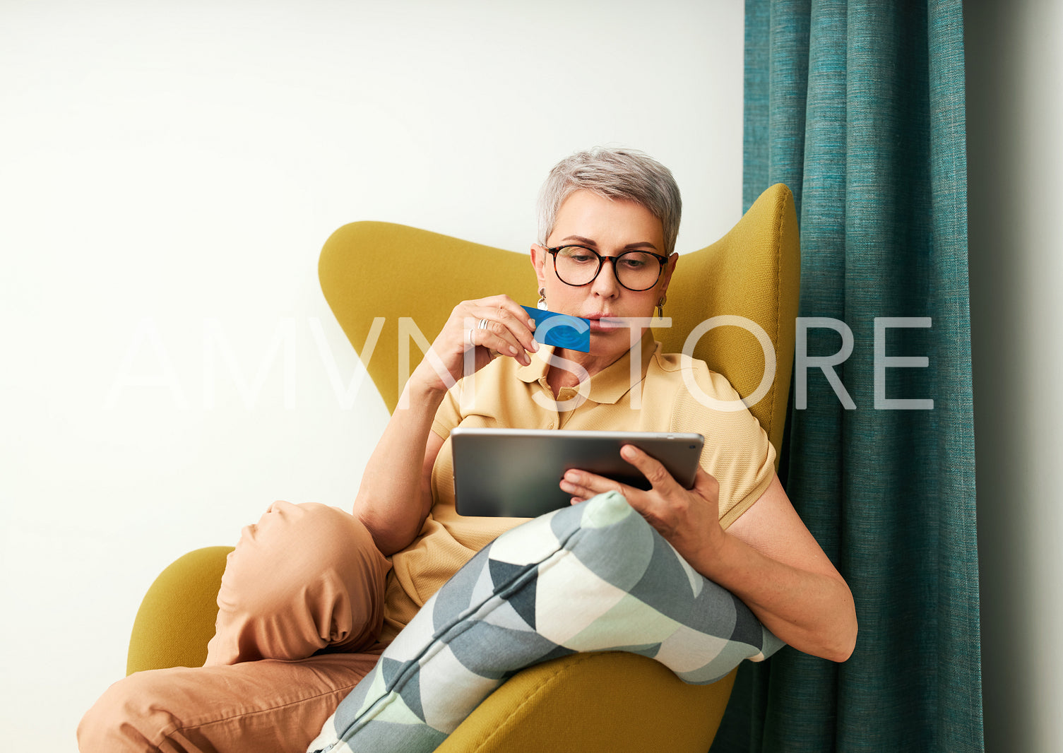 Mature woman in casuals paying by credit card while online shopping from home	