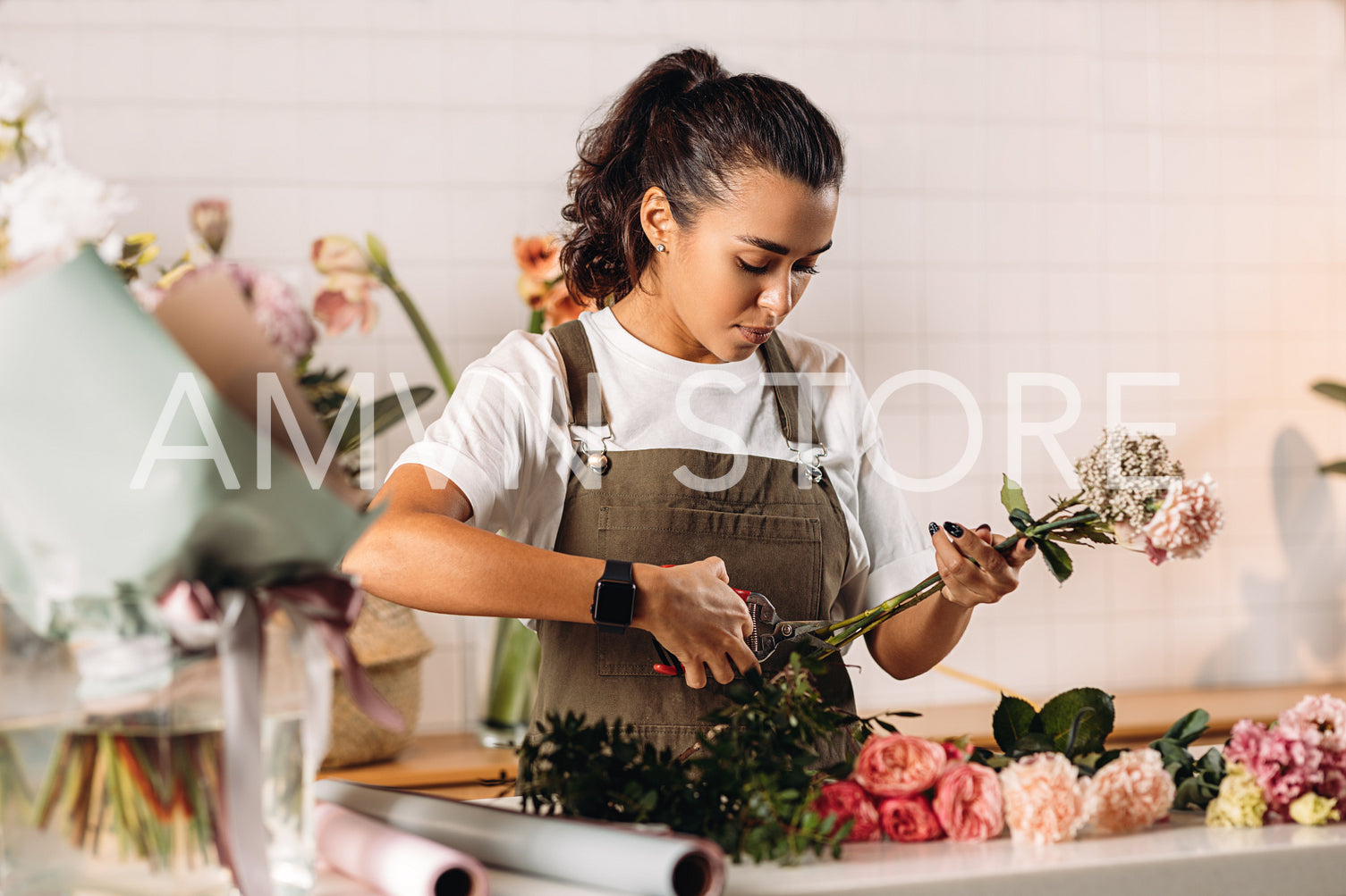 Woman florist cutting flowers with scissors and making bouquet on table	