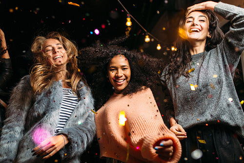 Group of female friends dancing, enjoying roof party with confetti