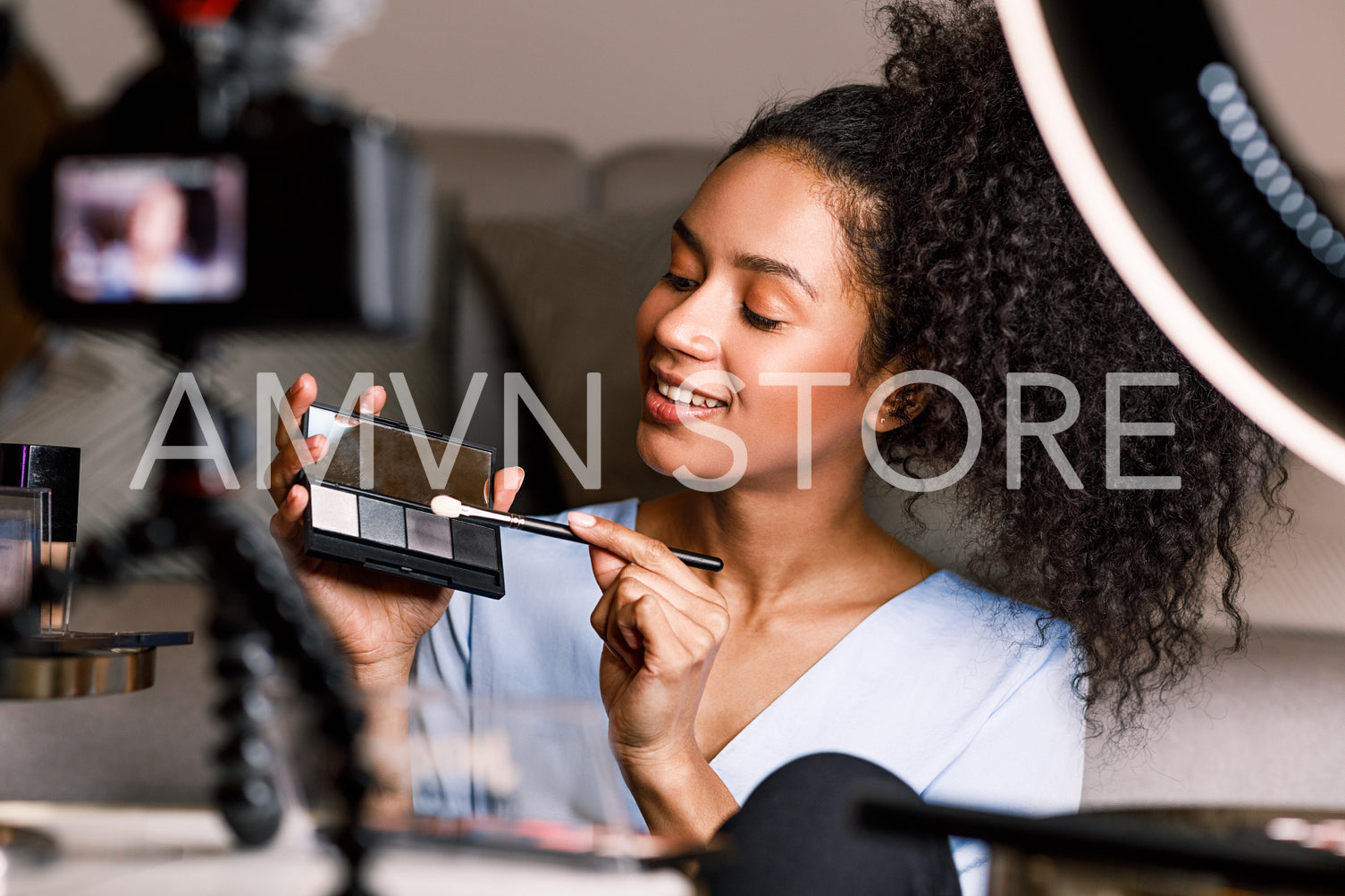 Beautiful woman holding a makeup palette while recording video at home	