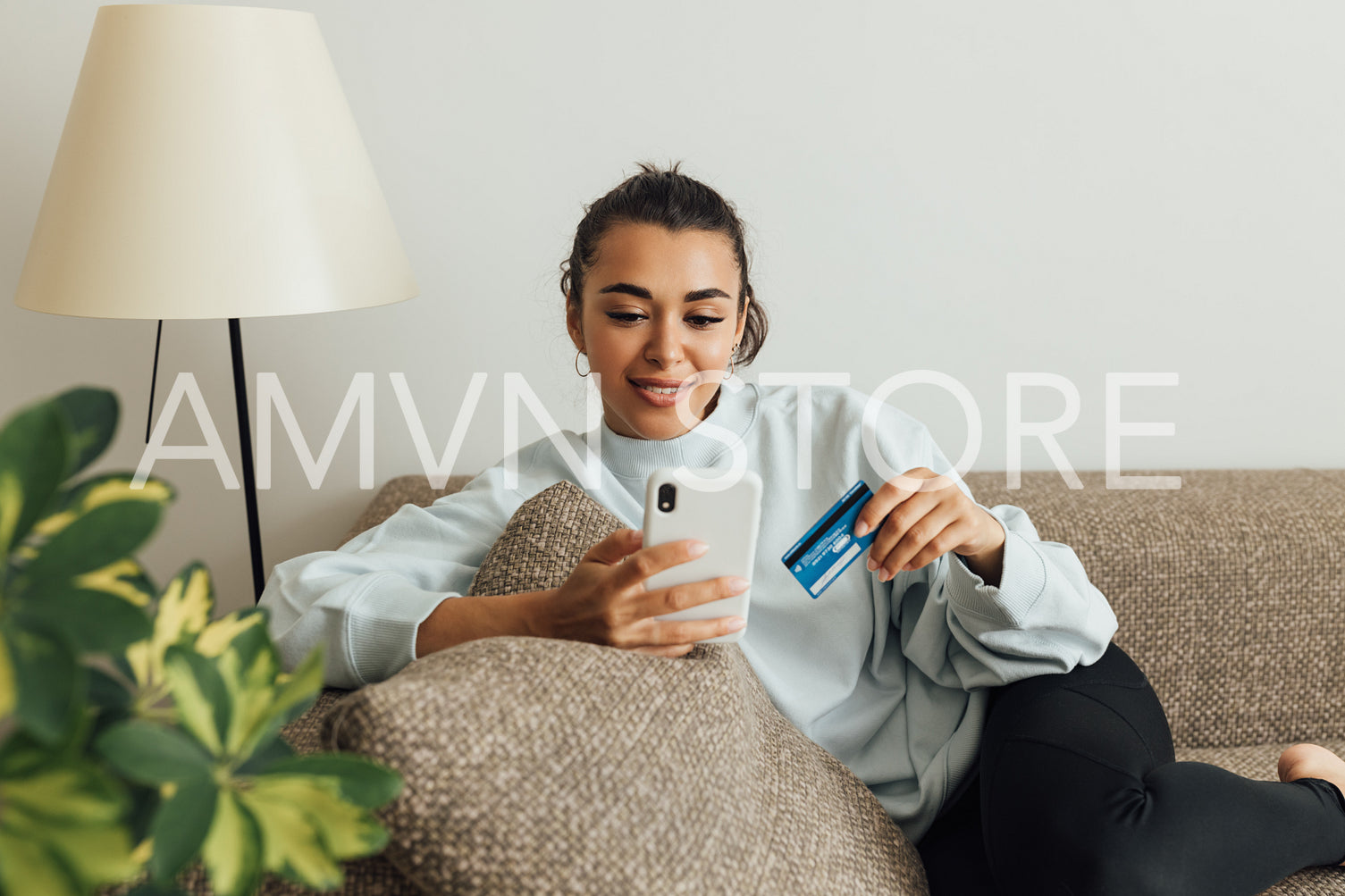 Woman in casual clothes relaxing on the sofa making online order with smartphone	