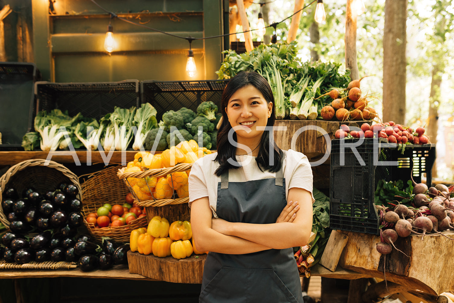 Portrait of a confident outdoor market employee. Smiling Asian woman in an apron standing at her outdoor stall.