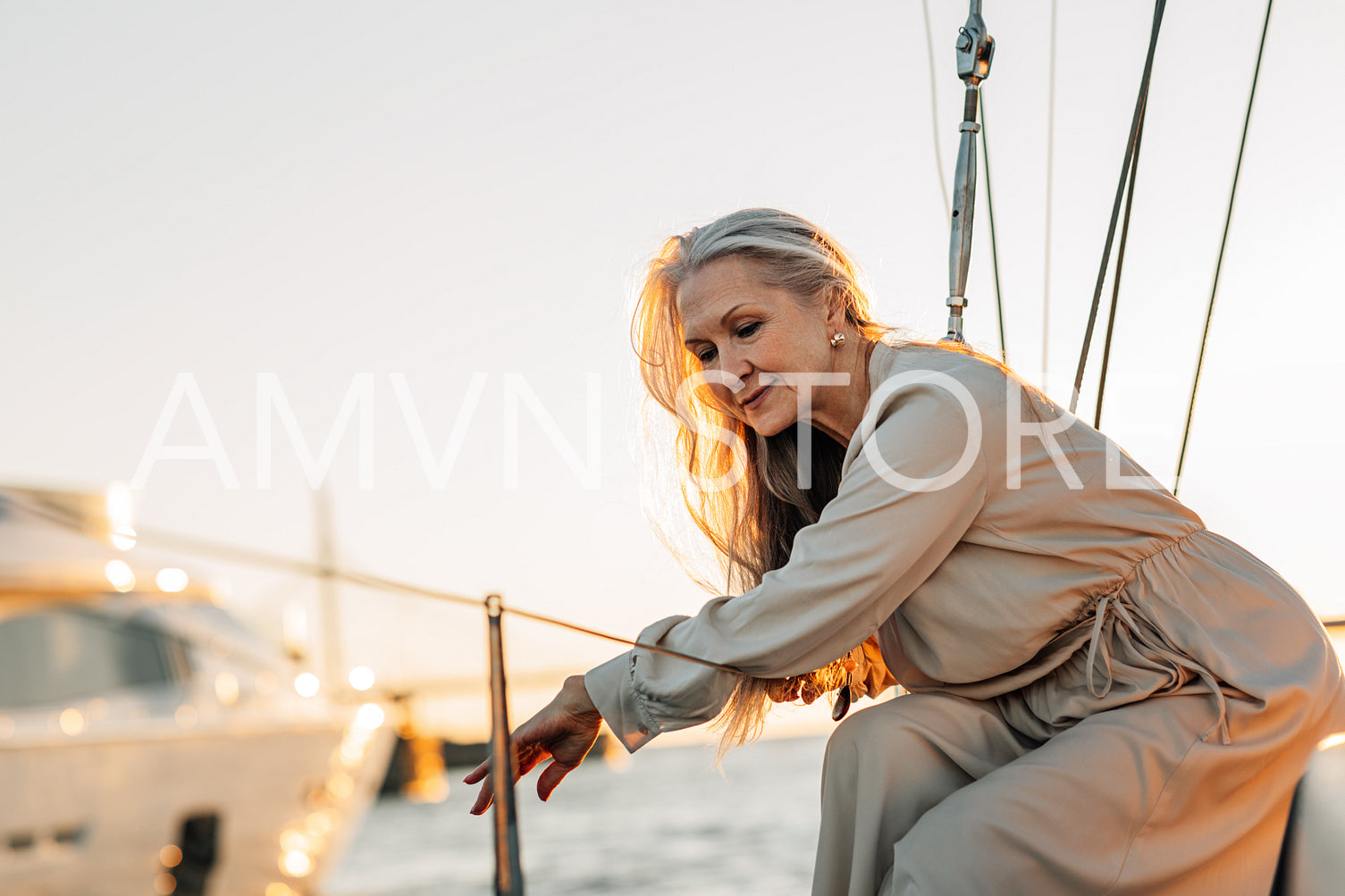 Stylish mature woman sitting on a yacht deck and looking on water	