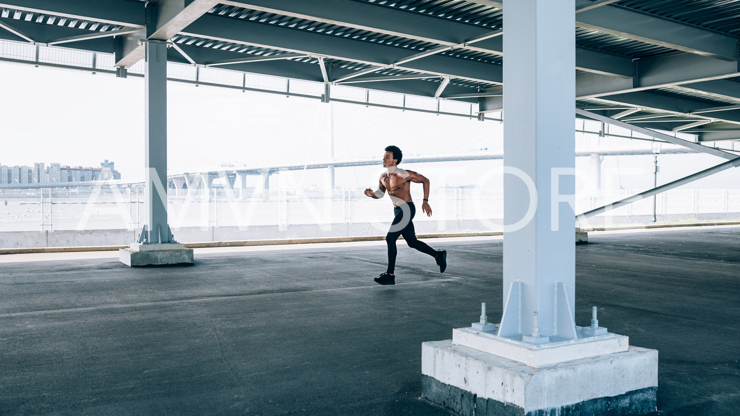 Male athlete running under a bridge. Man in fitness wear exercising outdoors.	