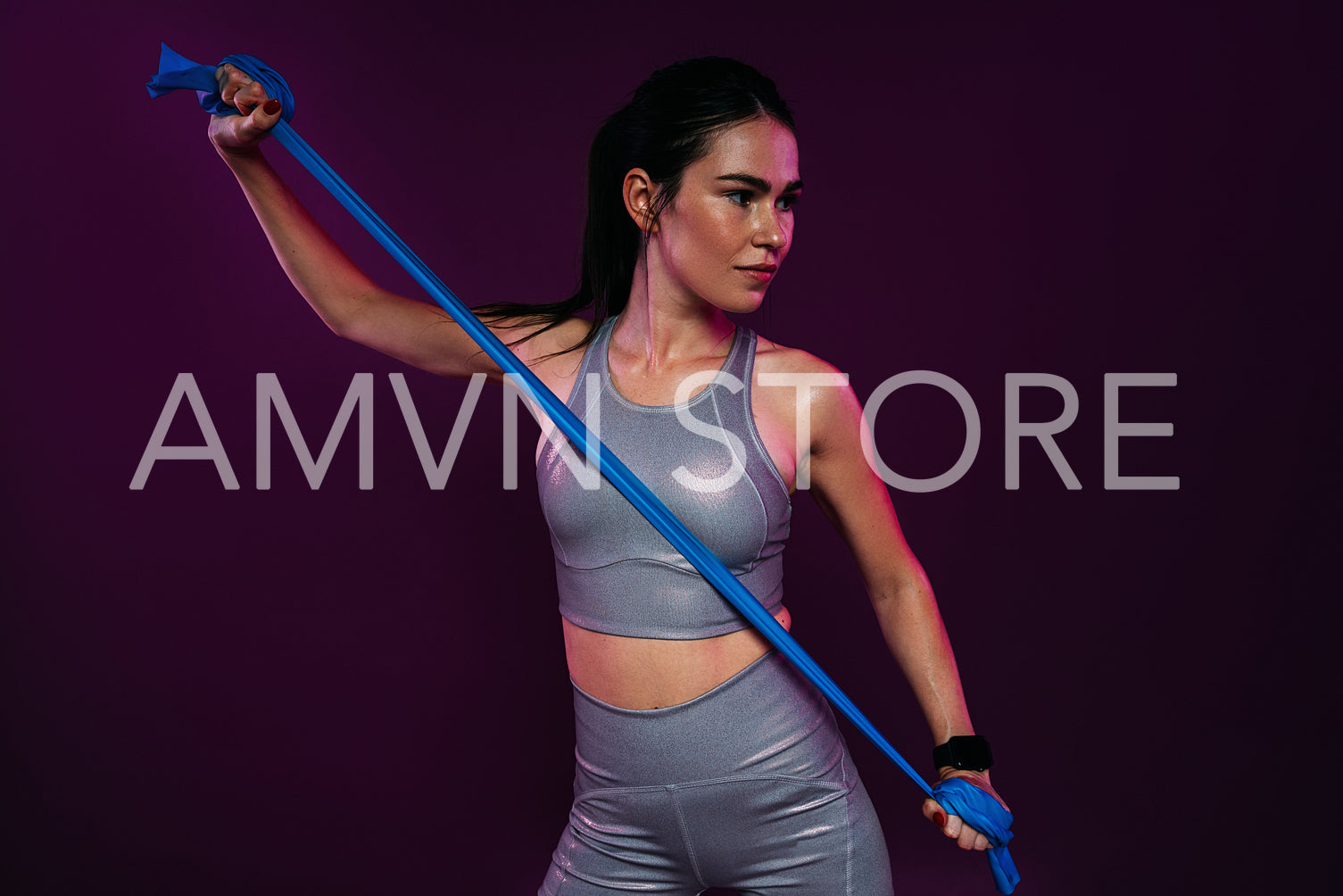 Slim woman exercising with resistance band against magenta backdrop