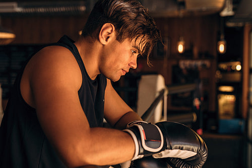 Side view of a tired and exhausted boxer standing in gym