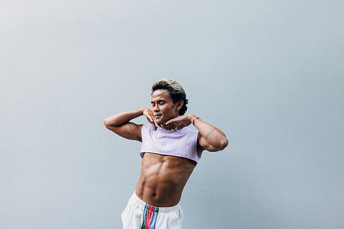 Young handsome man posing against grey wall in stylish clothes