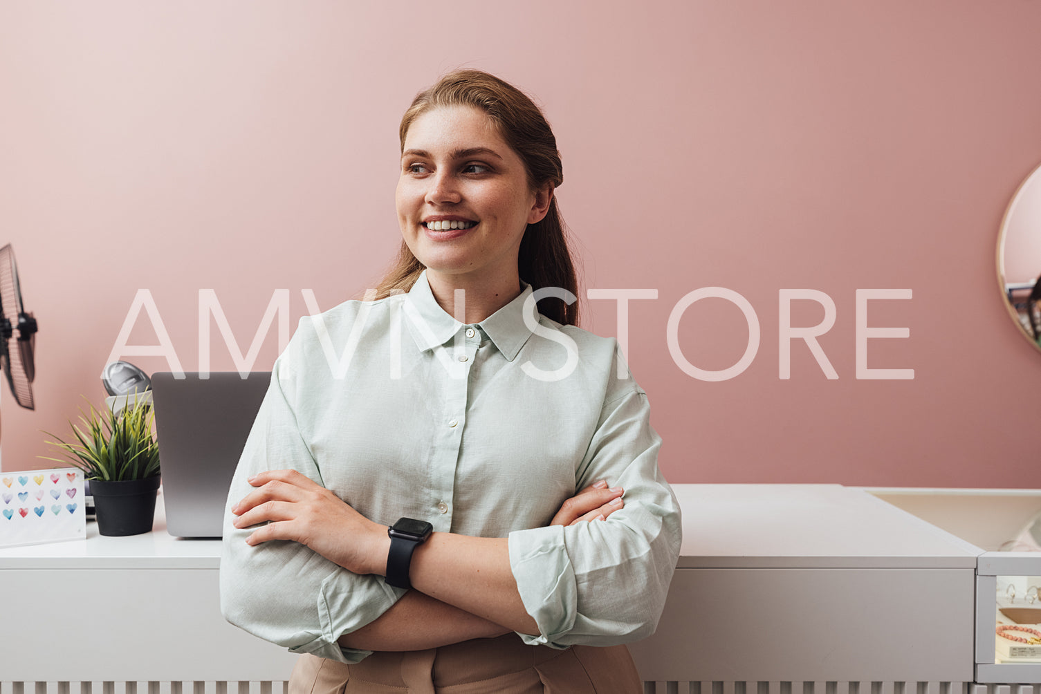 Smiling boutique owner standing at counter with crossed arms loo