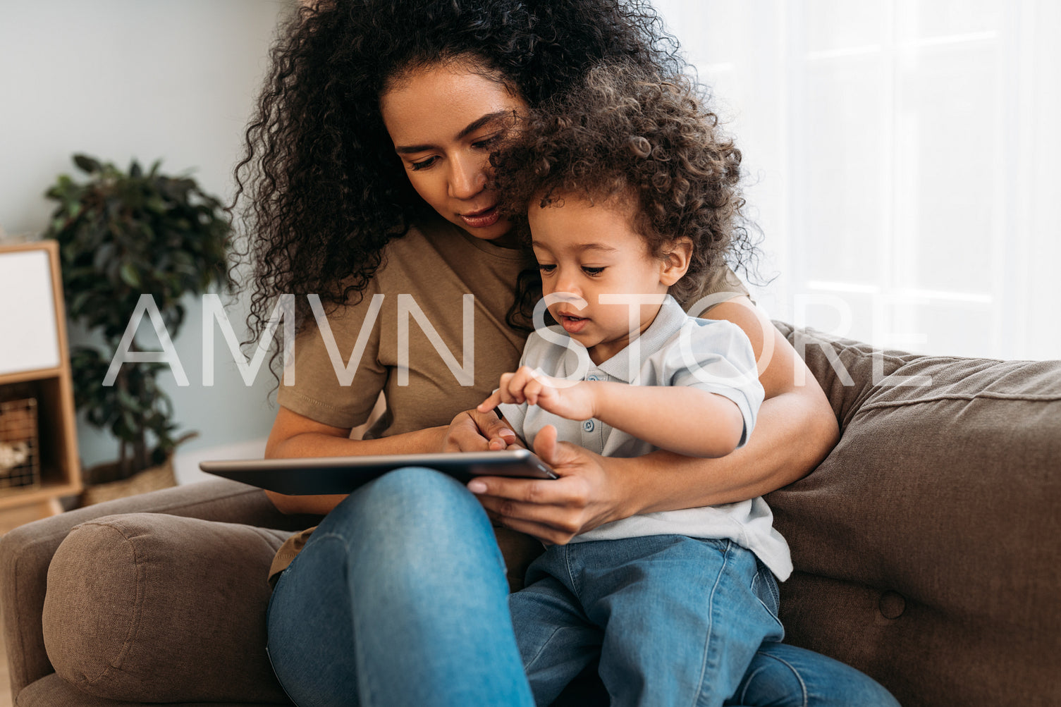 Mother and son sitting on the sofa and using digital tablet